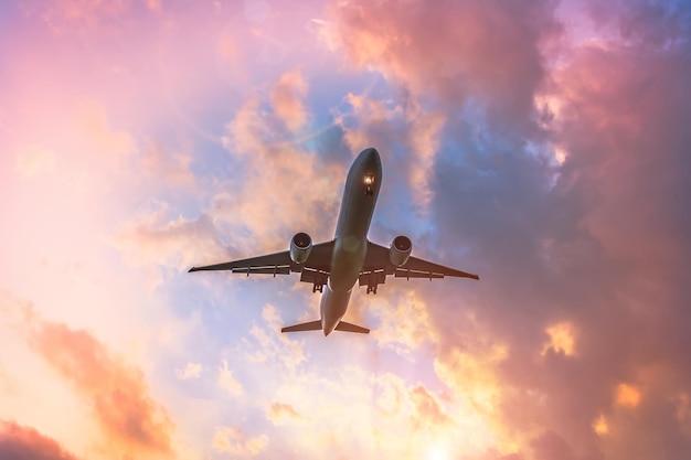 Silueta de avión en cálidos tonos amarillos y rosados del cielo y las nubes Copcept viaja a países más cálidos