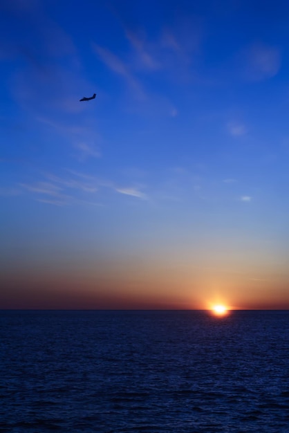 Silueta de avión sobre fondo de cielo al atardecer Hermoso paisaje marino fotografiado desde la cubierta del ferry