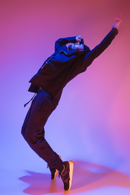 La silueta de un bailarín de break masculino de hip hop bailando sobre fondo de colores