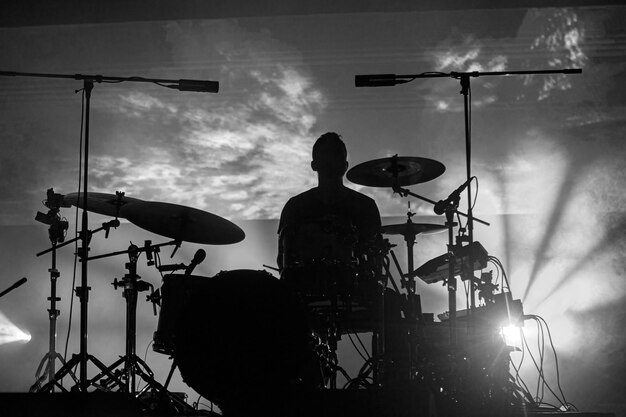 Foto una silueta de baterista de músico de rock durante un concierto en vivo en luz oscura