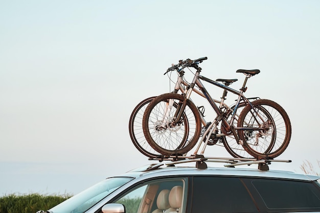 Silueta de bicicleta de montaña deportiva montada en el techo del automóvil con rayos de luz solar nocturna en el fondo Concepto de transporte de artículos seguros utilizando un automóvil con soporte de techo