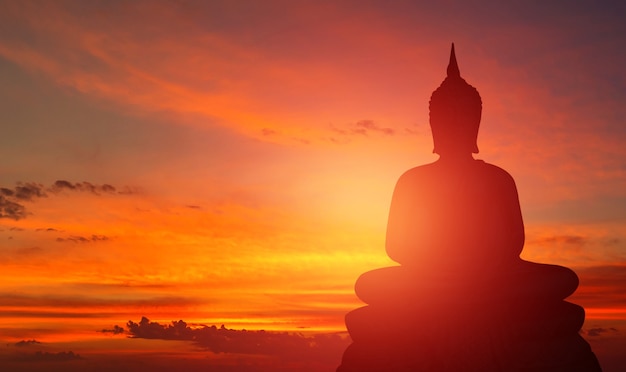 Silueta de Buda sobre fondo dorado atardecer creencias del budismo