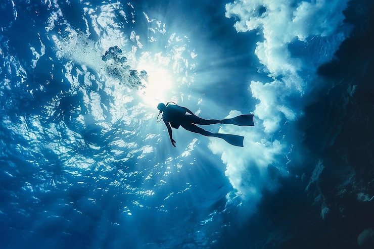 Foto silueta de un buzo en el mar azul con rayos de sol y luz solar