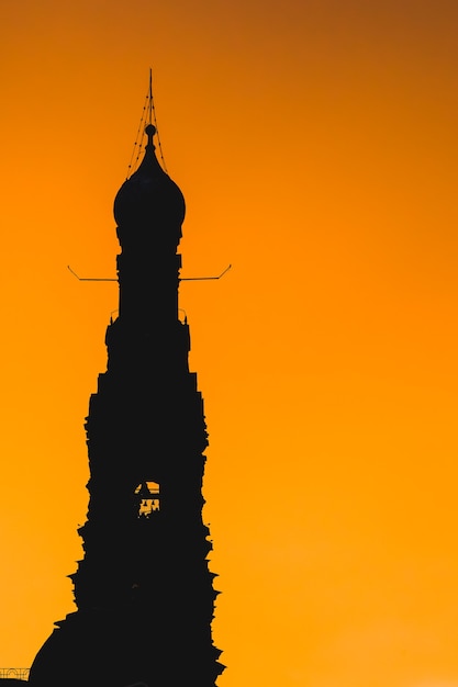 La silueta del campanario de la iglesia contra el fondo del cielo naranja