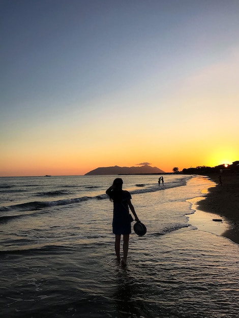 silueta de una chica mirando la puesta de sol en el mar
