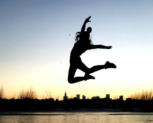 Foto silueta de una chica saltando al atardecer