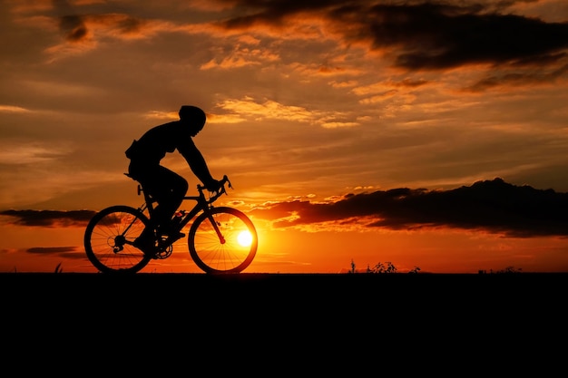 Silueta del ciclista en bicicleta de carretera al atardecer.