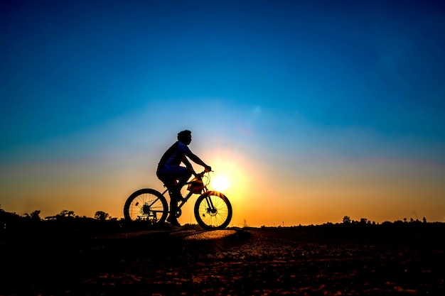 Silueta del ciclista en fondo de la puesta del sol.