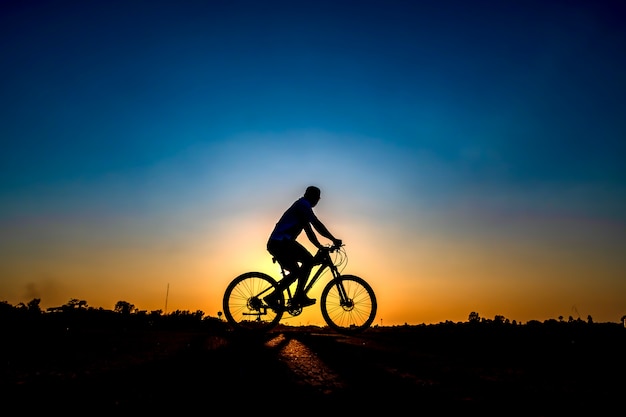 Foto silueta del ciclista en fondo de la puesta del sol.