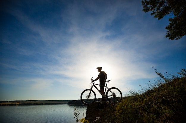 Silueta del ciclista montando una bicicleta de carretera al atardecer. Bicicleta de montaña y hombre. Estilo de vida al aire libre