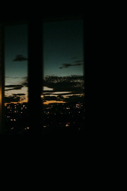 Foto silueta de la ciudad vista a través de una ventana de vidrio por la noche