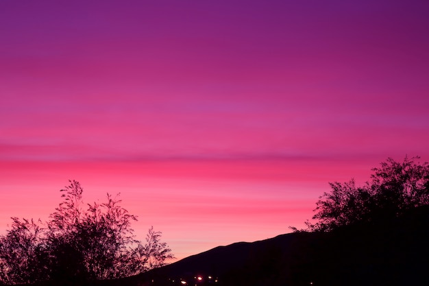 Silueta de colina y árboles con cielo púrpura de ensueño