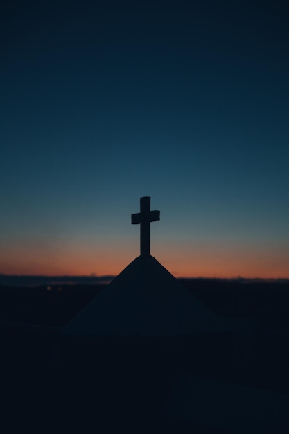 La silueta de la cruz contra el cielo despejado durante la puesta de sol