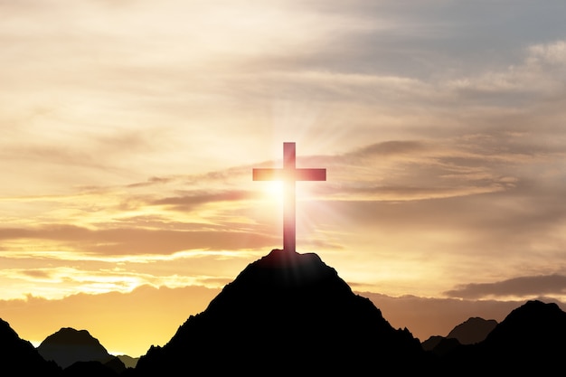 Silueta de la cruz o crucifixión de Jesús Christian en la cima de la montaña con la luz del sol y el cielo de nubes. Concepto de religión del cristianismo.