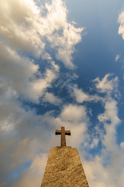 Foto silueta de cruz de tumba de piedra contra el fondo de un cielo azul de la tarde con nubes