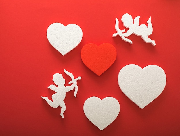 Silueta de cupido volador con corazones, regalos, pancartas de feliz día de San Valentín, estilo de arte en papel. Amour sobre papel rojo