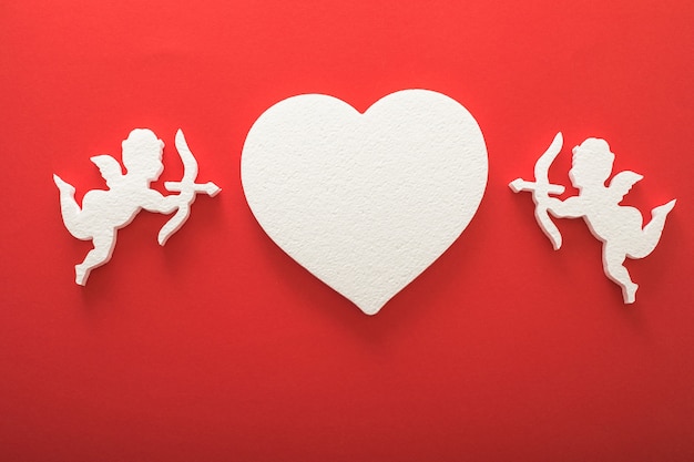 Foto silueta de cupido volador con corazones, regalos, pancartas de feliz día de san valentín, estilo de arte en papel. amour sobre papel rojo