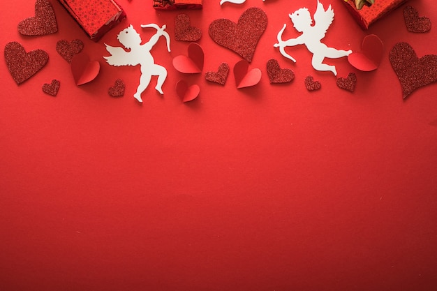 Silueta de cupido volador con corazones, regalos, pancartas de feliz día de San Valentín, estilo de arte en papel. Amour sobre papel rojo