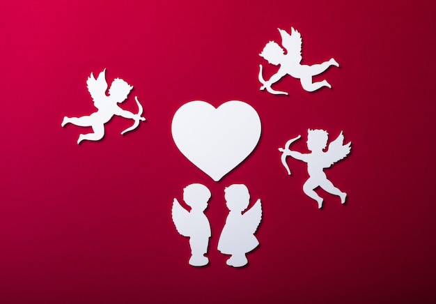 Silueta de cupido volador, dos ángeles blancos, pancartas de feliz día de San Valentín, estilo de arte de papel. Amour sobre papel rojo