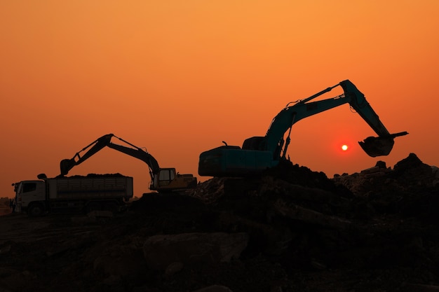 Silueta, de, carregador escavador, em, local construção, em, céu ocaso, fundo