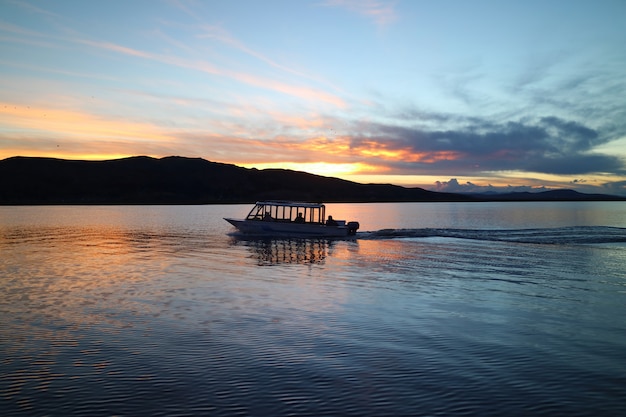 Silueta, de, um, barco cruzando, ligado, lago titicaca, em, pôr do sol, puno, peru