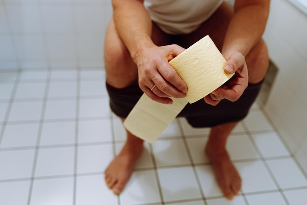 la silueta desenfocada de un hombre irreconocible está sentada en el inodoro. problemas urinarios relacionados con la edad