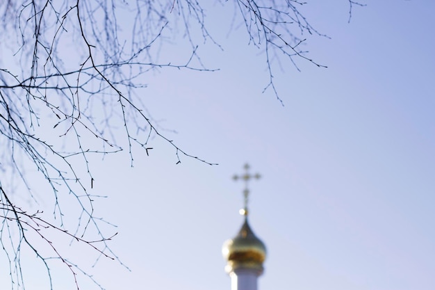 silueta desenfocada de la iglesia ortodoxa con cielo azul y ramas de abedul desnudas