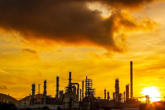 Silueta de destilación de gas de la torre de la planta de refinería de petróleo del tanque y aceite del tanque de columna de la industria petroquímica en el fondo del atardecer del cielo