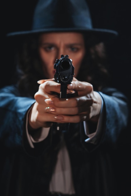 Silueta de una detective con abrigo y sombrero con una pistola en las manos apuntando a la cámara Un retrato de drama noir de libro al estilo de los detectives de la década de 1950