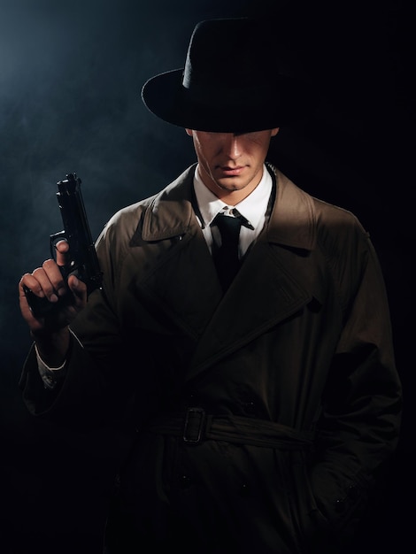 Silueta de un detective con abrigo y sombrero con una pistola en las manos