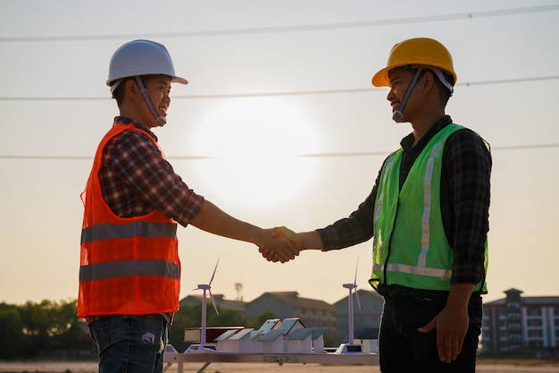 Silueta de dos arquitectos dándose la mano en el sitio de construcción durante la puesta de sol