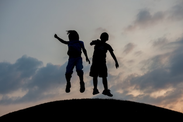 Foto silueta de dos hermanos disfrutando de la libertad