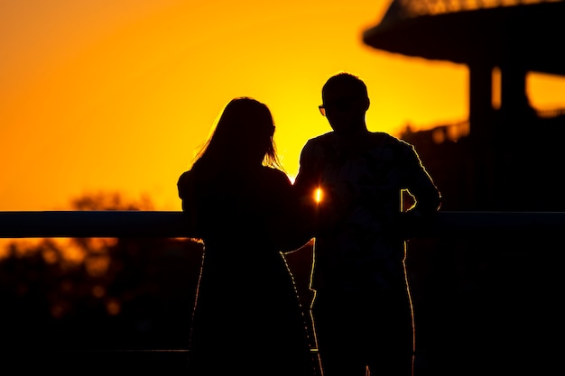 Silueta de dos personas enamoradas con el telón de fondo del sol poniente. Romance en las relaciones y la naturaleza.