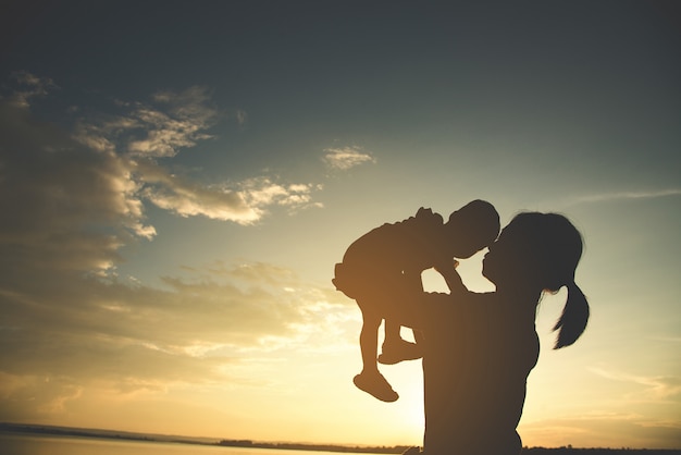 Una silueta de una familia armoniosa de la madre joven feliz al aire libre.