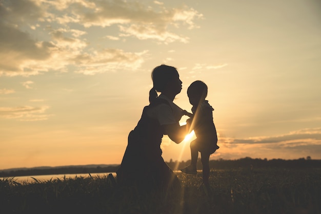 Una silueta de una familia armoniosa de la madre joven feliz al aire libre.