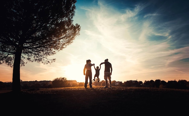 Silueta de familia feliz caminando en la pradera al atardecer