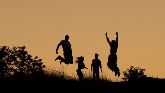 Silueta de una familia feliz de cuatro, madre, padre, hija, hijo al atardecer