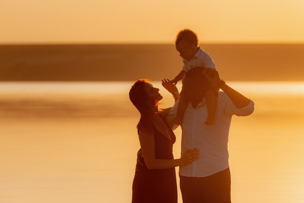 Silueta de familia feliz en la playa en un hermoso día de verano. Familias caminando por la noche