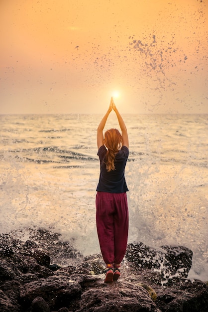 Silueta femenina en pose de meditación Yoga al atardecer increíble en la playa