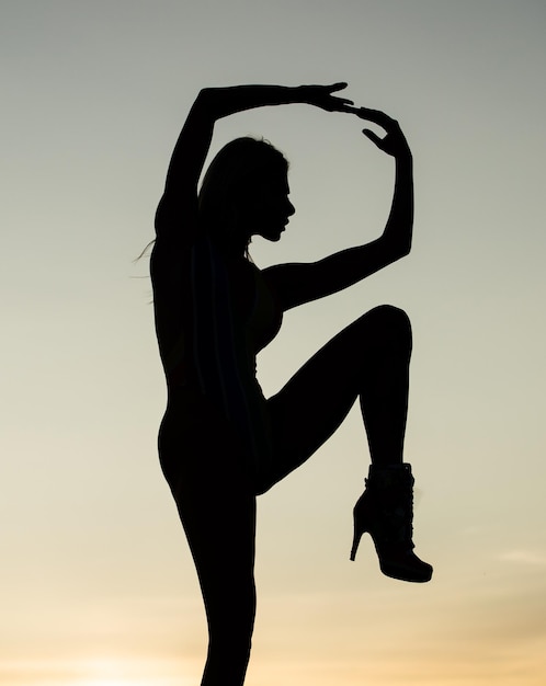 Silueta femenina sobre fondo de cielo al atardecer de silueta de mujer bailando