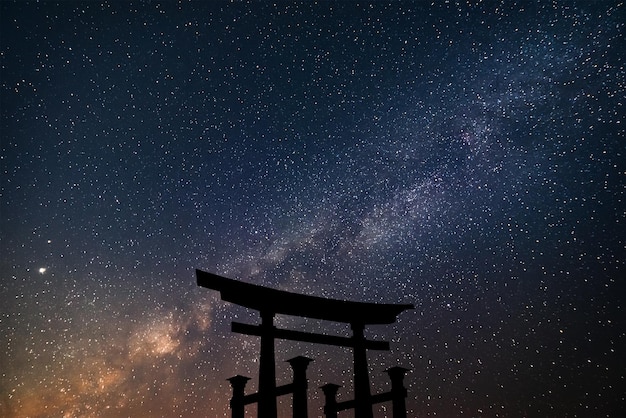 Silueta flotante torii en el cielo estrellado con la puerta del santuario sintoísta de fondo de la vía láctea