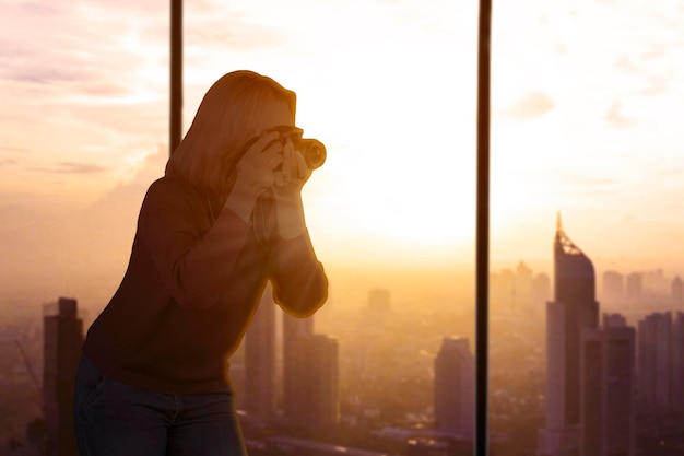 Silueta de fotógrafa tomando fotos del paisaje urbano durante la puesta de sol