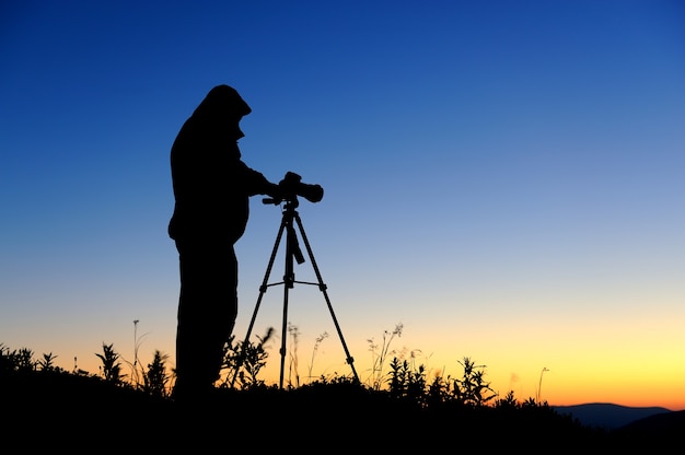 Silueta de un fotógrafo de paisajes en el crepúsculo