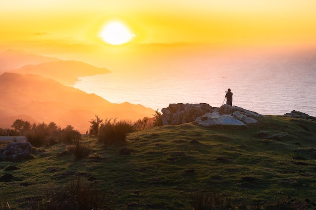 Foto silueta de fotógrafo tomando fotos en la cima de la montaña jaizkibel al atardecer