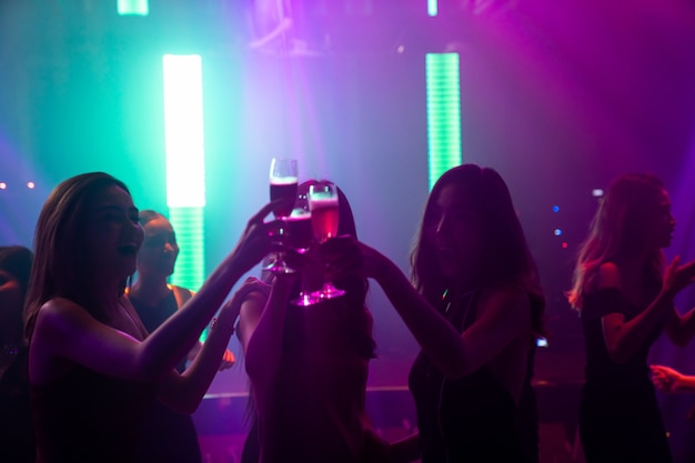 Silueta de gente baila en discoteca con música de DJ en el escenario