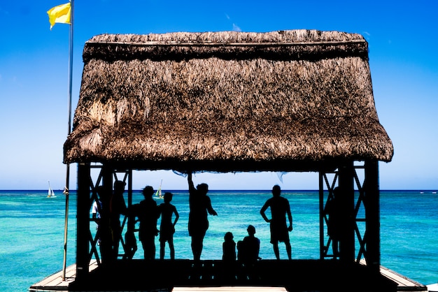 Silueta de gente descansando en una casita en el muelle del mar.