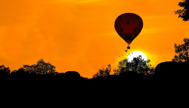 Silueta de globo de aire caliente sobre fondo puesta de sol