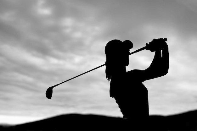 Foto silueta de un golfista balanceándose en el fondo del cielo