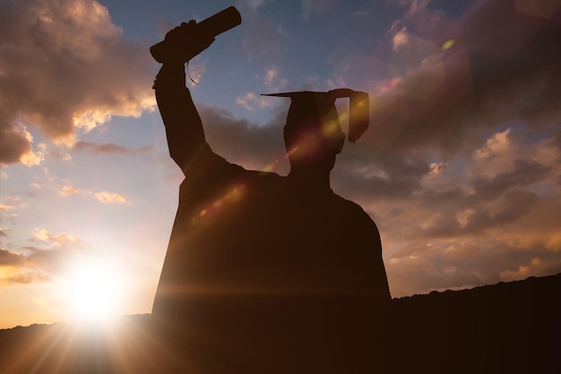 Foto silueta de graduado contra el sol brillando