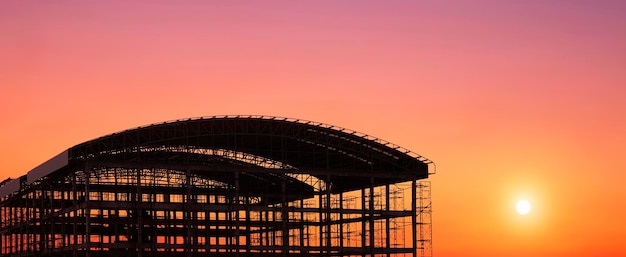 Silueta de gran estructura de edificio industrial contra el colorido cielo del atardecer en vista panorámica